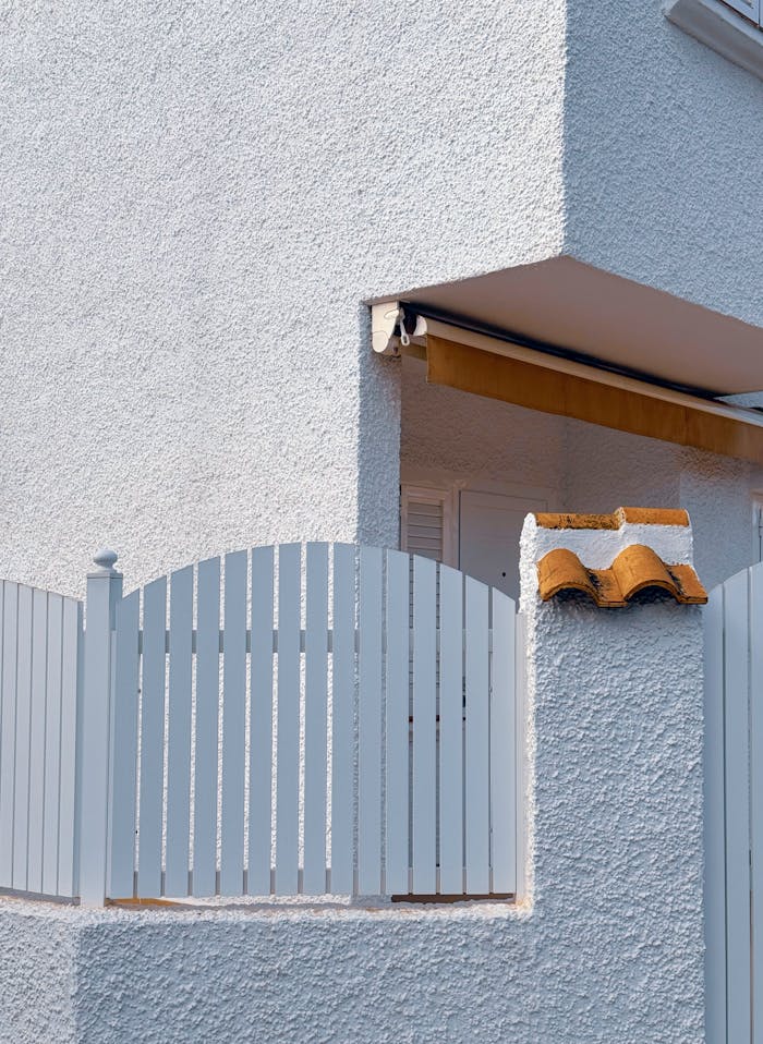 Close-up of a white stucco house corner with fence, Spain.